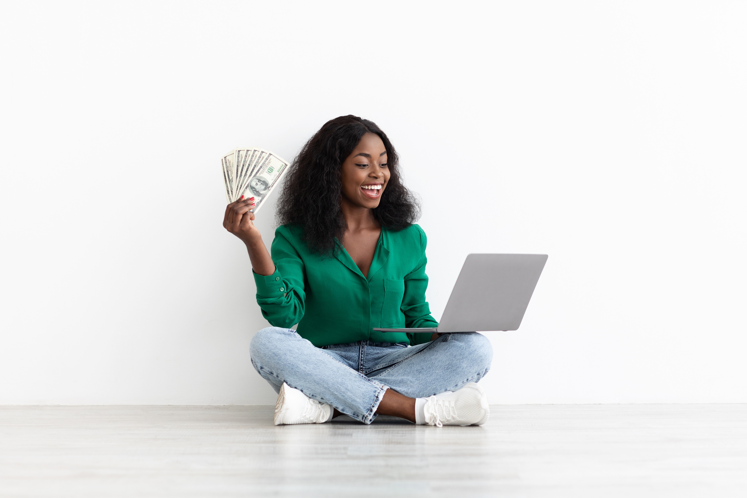 Happy African American Lady Gambling Online, Holding Laptop and Money
